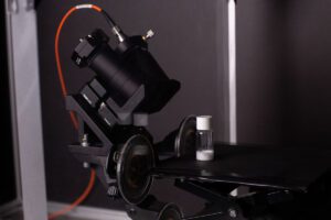 Suction cup probe mounted to exterior of a freeze-dryer measuring white powder in a glass vial