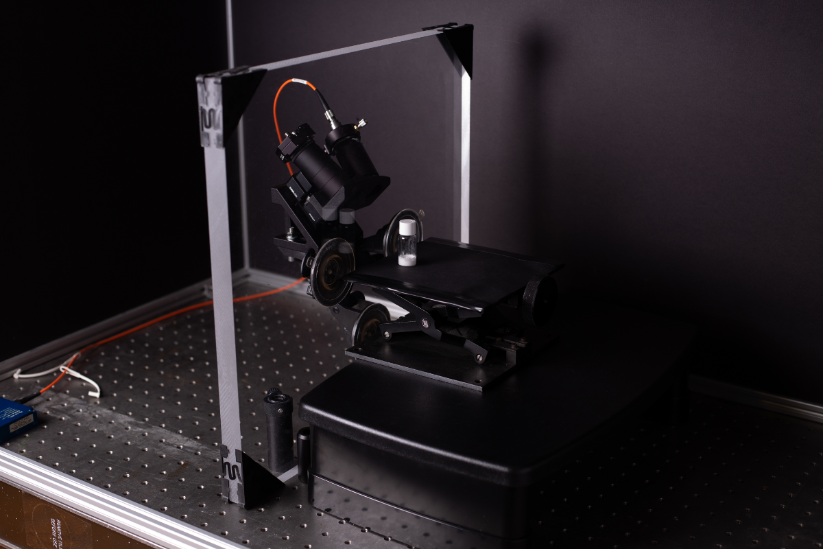 Suction cup Raman probe mounted to acrylic measuring white powder in a glass vial